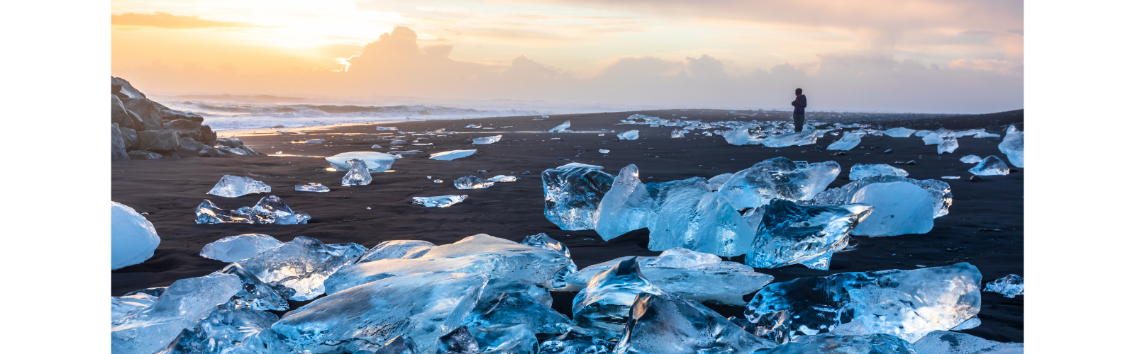 A lone, shadowy figure stands in a field of ice clumps as the sun rises. 